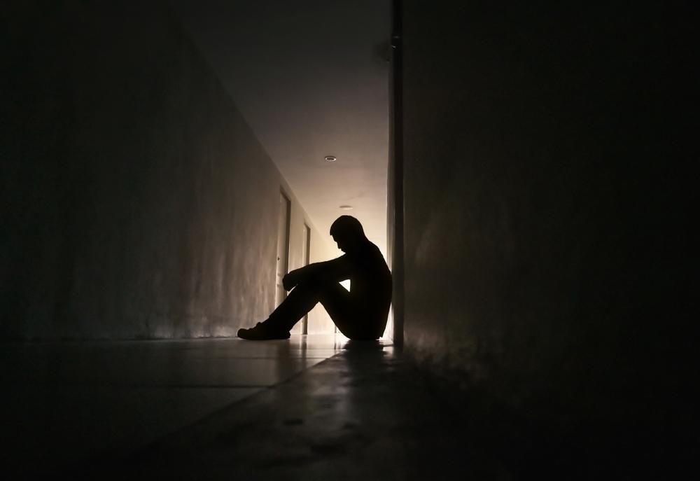 Depressziós férfi sziluettje, aki egy lakóépület folyosóján ül