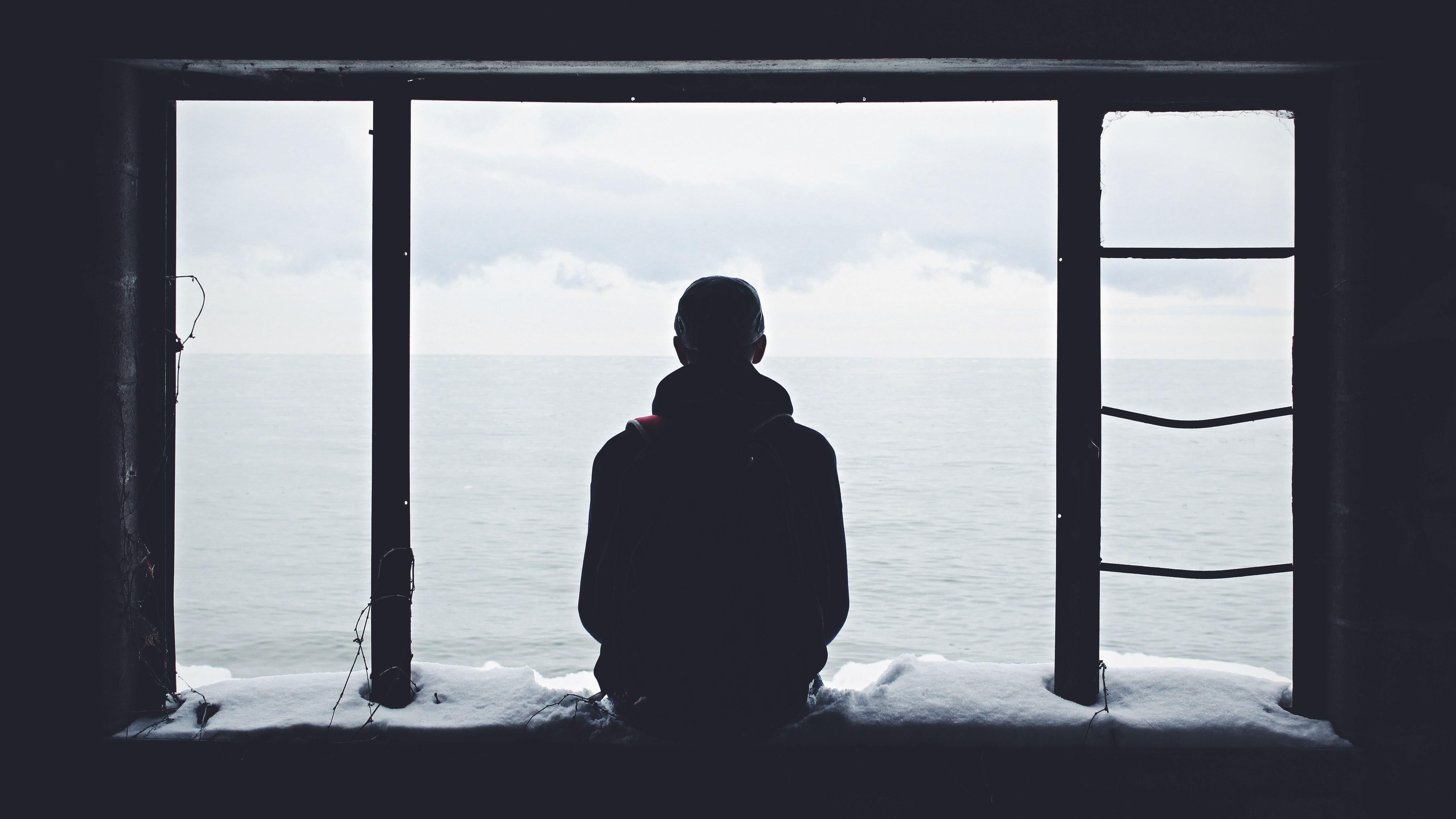 Egy szomorú ember egyedül ül az ablakban