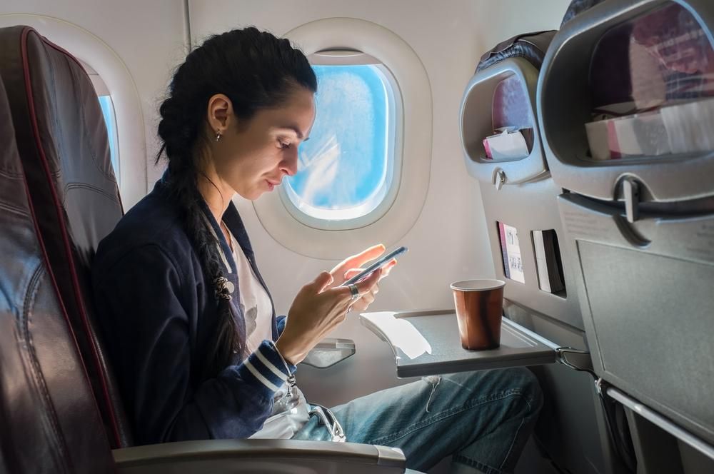 Repülőgépen mobiltelefonozó nő