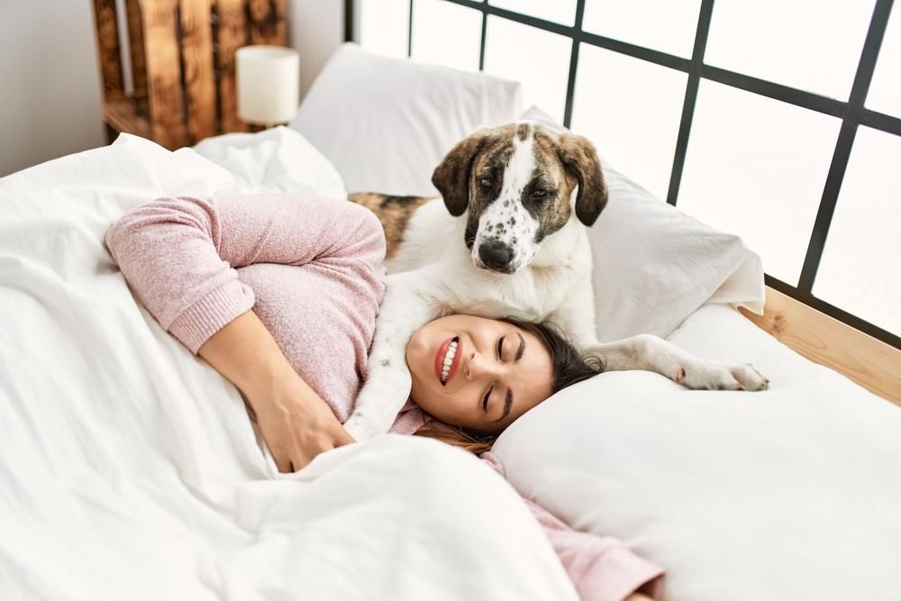 Kutyájával az ágyban alvó nő