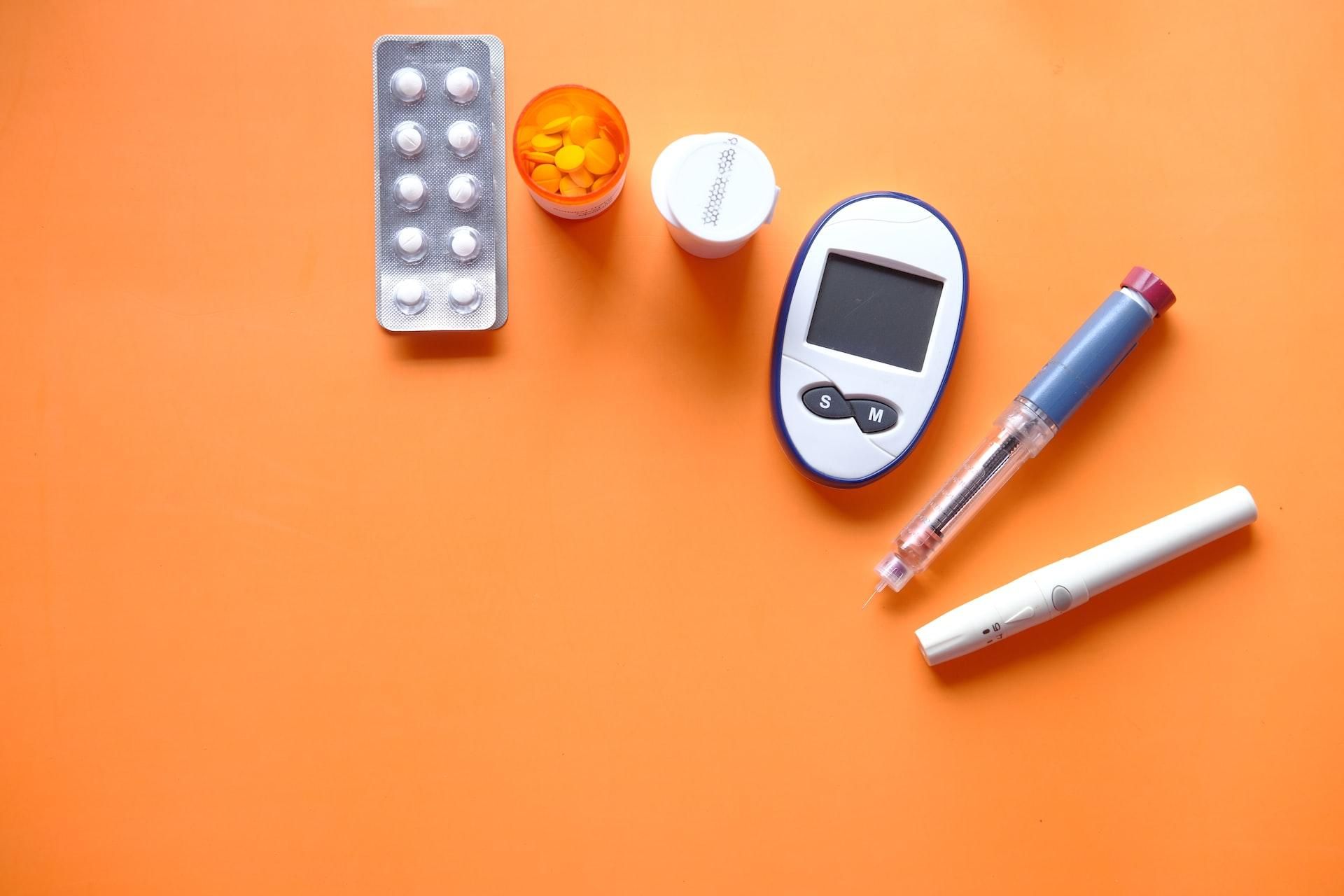 inzulin, diabetikus mérőeszközök és tabletták narancssárga háttéren