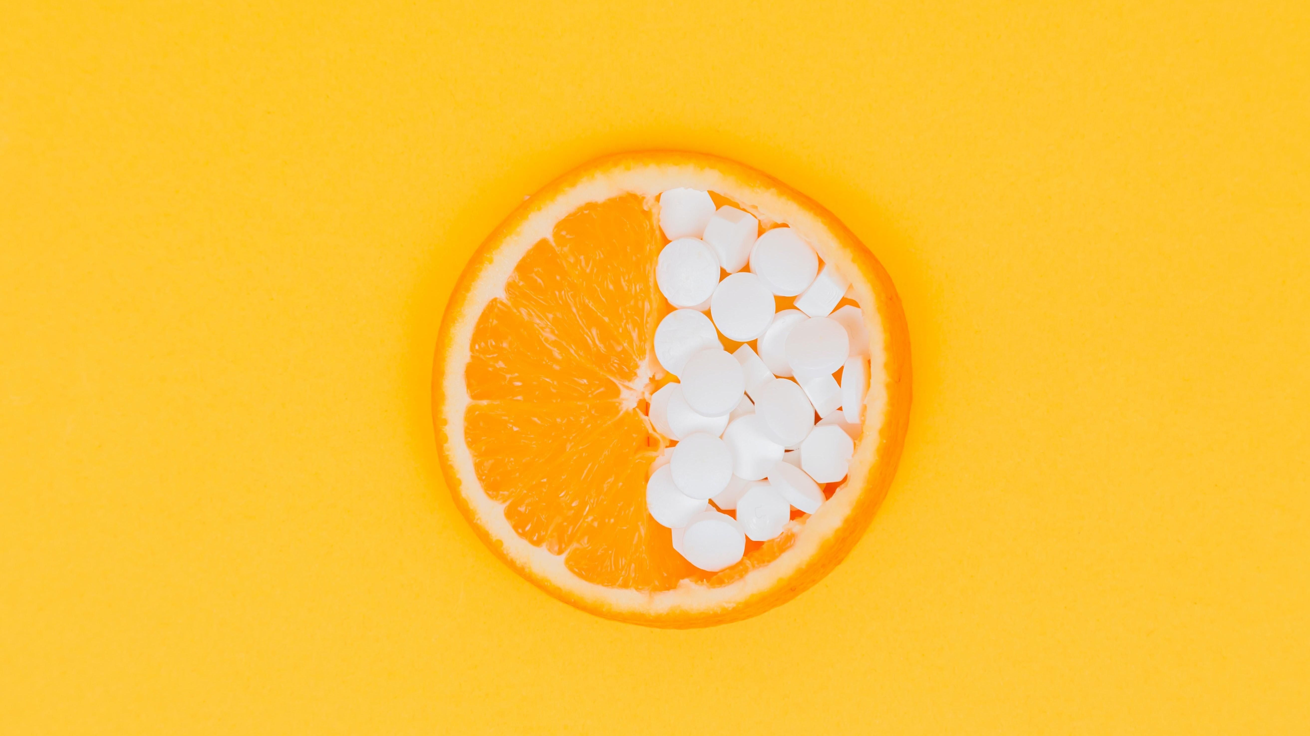 Egy narancs, aminek az egyik felébe C-vitamintablettákat tettek