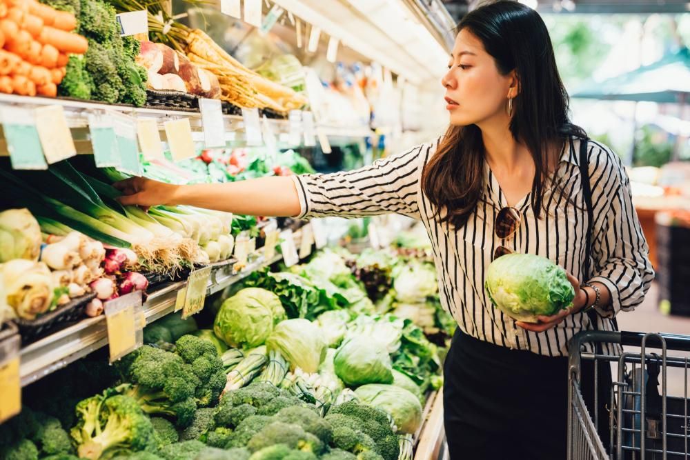 Zöldségek és gyümölcsök között válogató nő a szupermarketben
