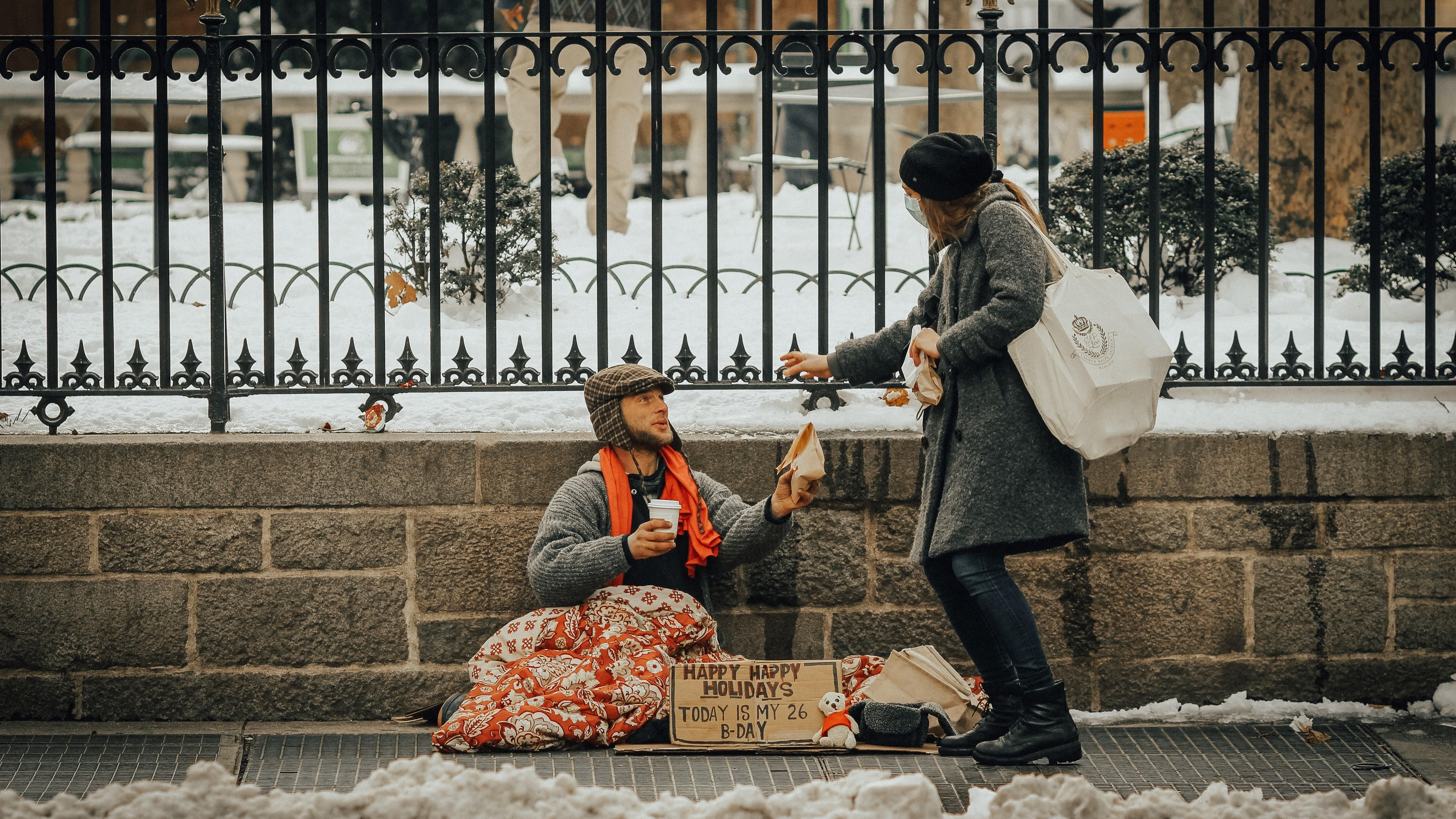 Egy járókelő kisegít egy földön ülő hajléktalant