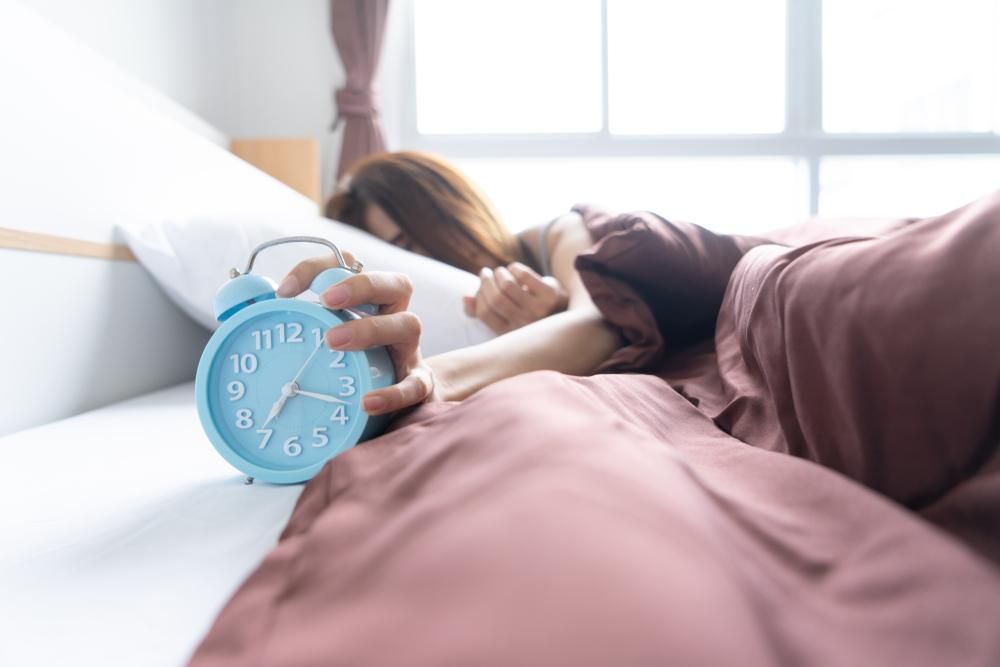 A csörgő ébresztőórát lenyomó, ágyban fekvő nő