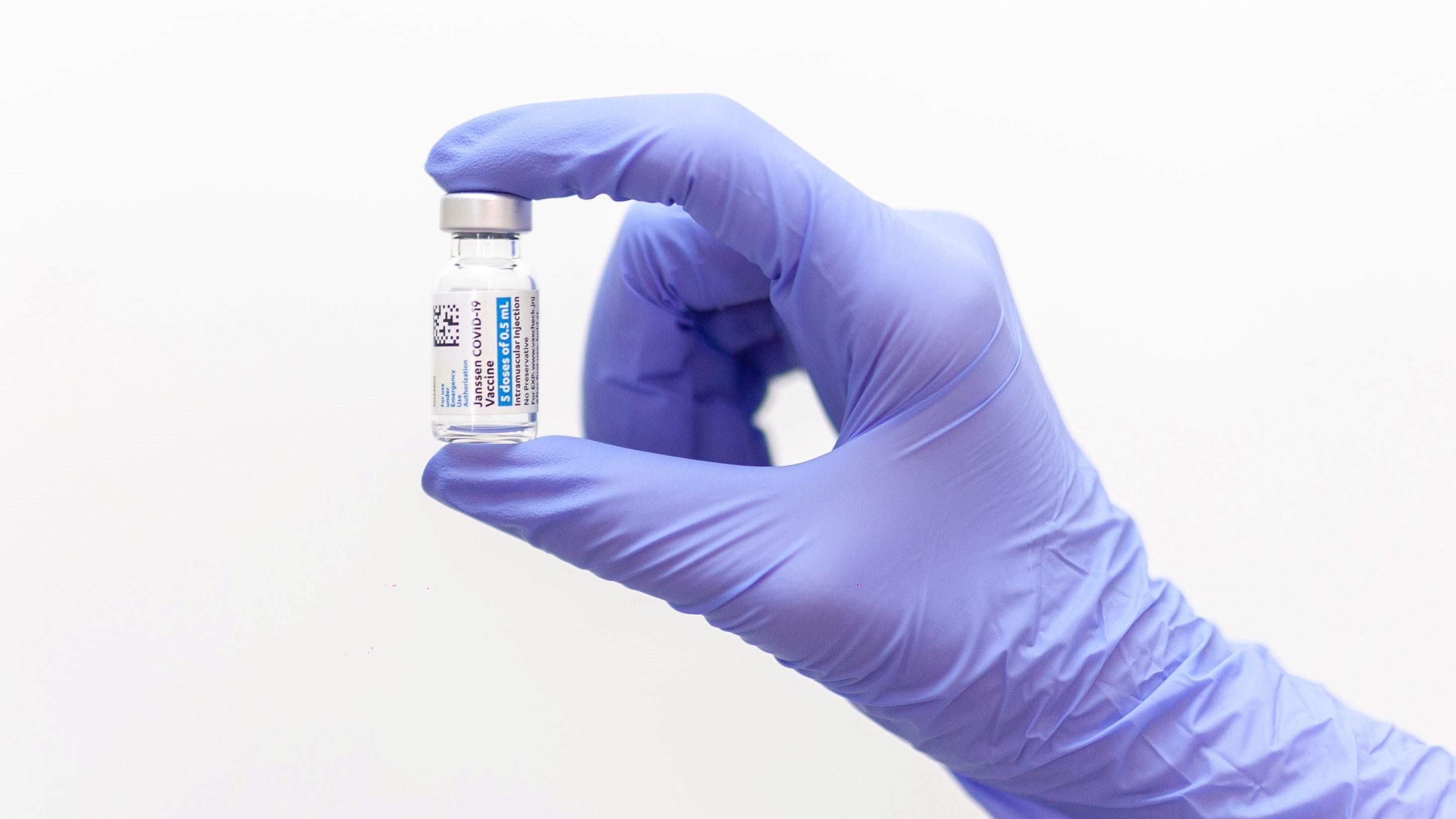 Egy gumikesztyűs ember koronavírus elleni vakcinát tart a kezében