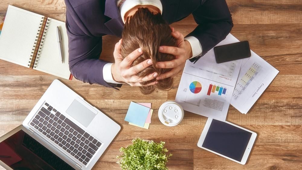 Egy férfi stressz miatt fogja a fejét a munkahelyén