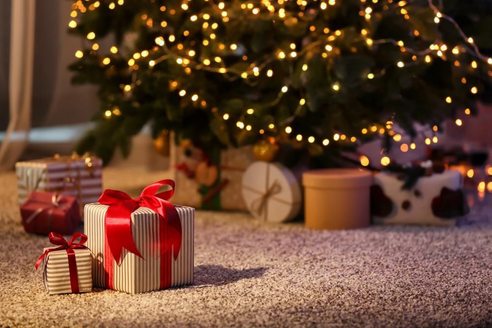 Karácsonyi ajándékok a földön, háttérben karácsonyfa 