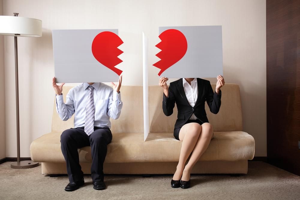 Összetört szív formákat ábrázoló plakátokat tartó férfi és nő