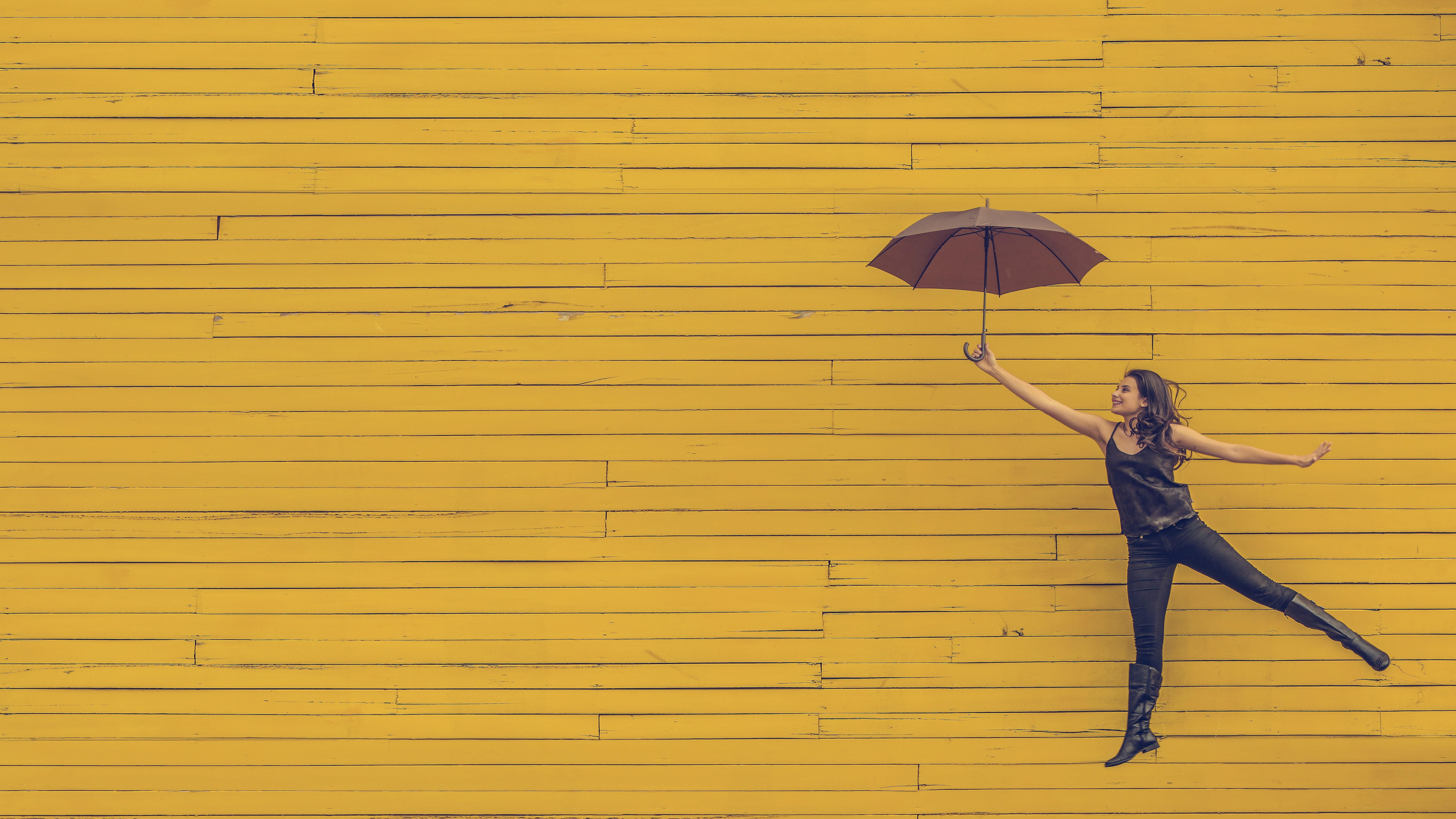 Egy lány esernyővel a kezében egy sárga háttér előtt