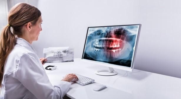 Fogak panorámaröntgenjét a számítógépen néző fogorvos