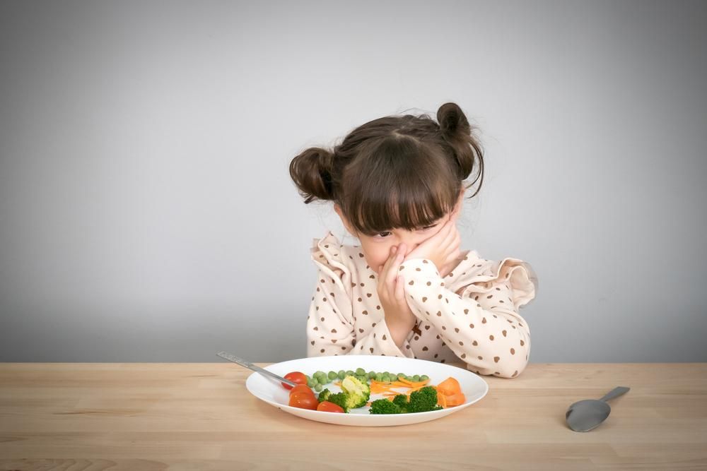 A tányérján lévő zöldségektől undorodó kislány