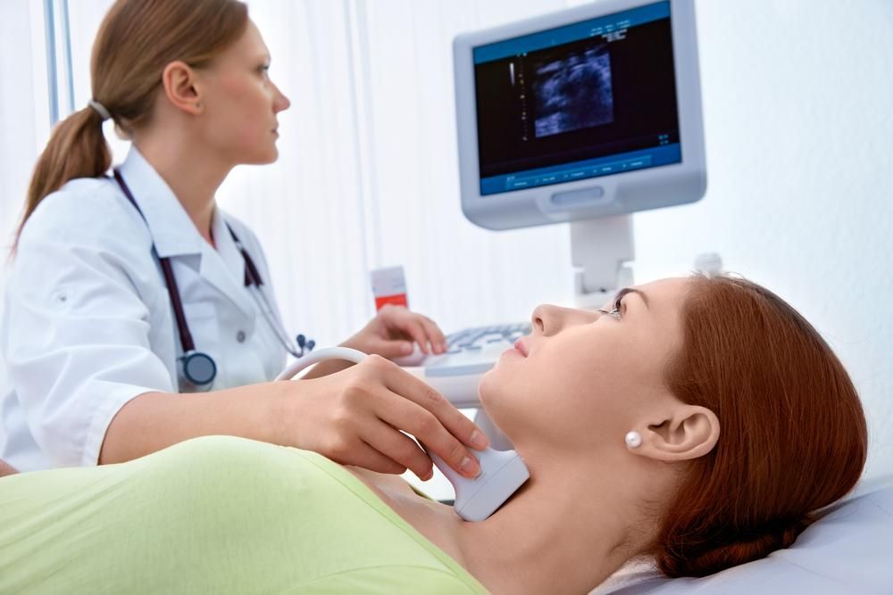 Női páciens pajzsmirigyét ultrahanggal vizsgáló orvos