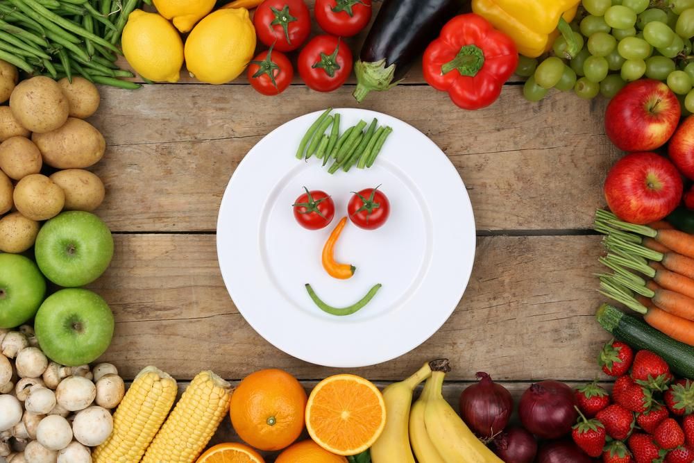 Mosolygó arc a tányéron lévő zöldségekből és gyümölcsökből
