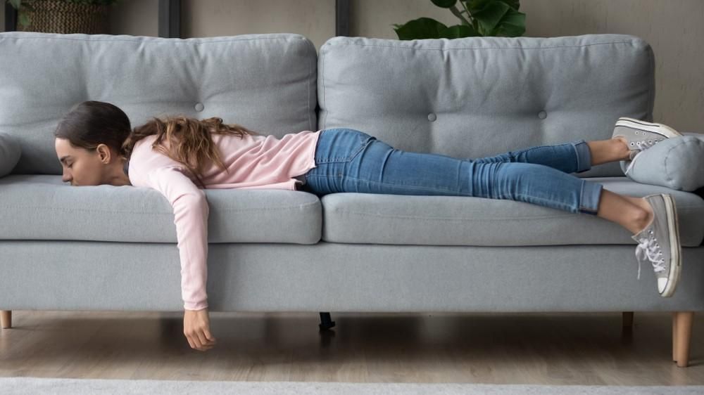 Egy nő unatkozik és hason fekszik a kanapéján