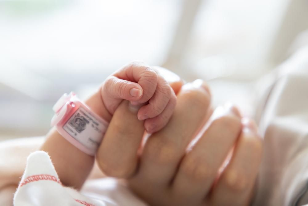 Újszülött csecsemő keze fogja a szülő ujját