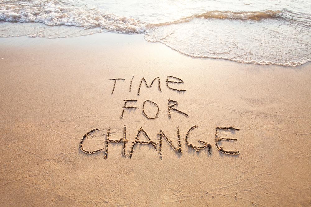 A változás ideje felirat angolul a tengerparti homokba írva