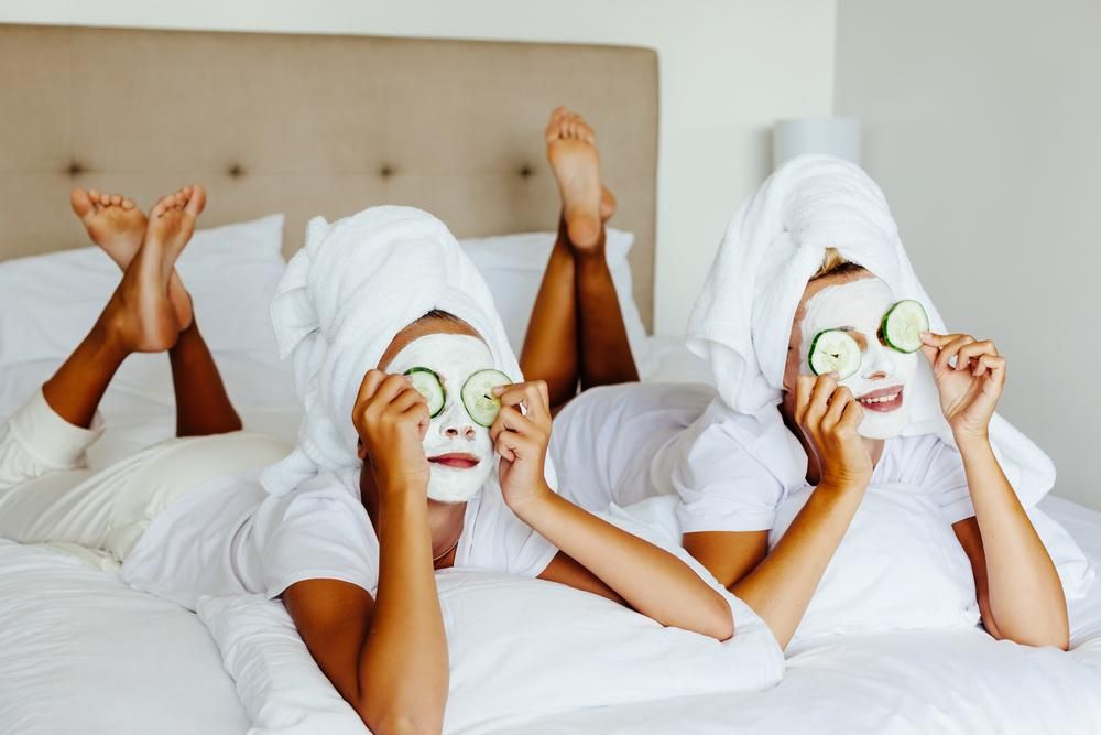 Két nő az ágyon, arcukon agyagmaszkkal és uborkaszeletekkel