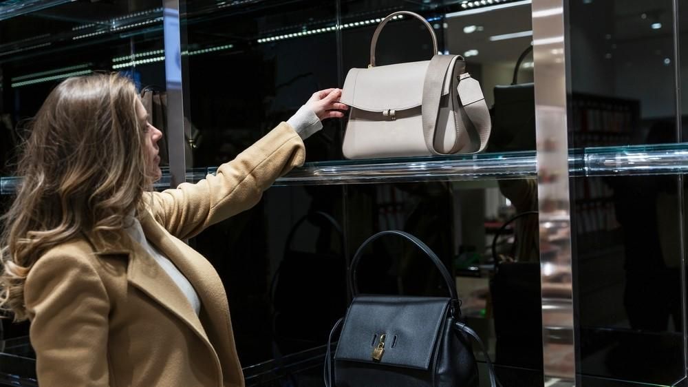 Egy nő egy táskát vesz le egy üzlet polcáról