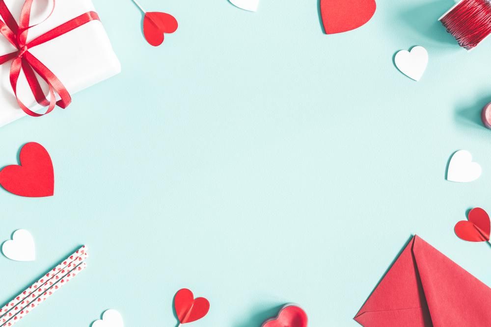 Valentin-napi koncepció: ajándékok, gyertya, konfetti, boríték pasztell kék háttéren
