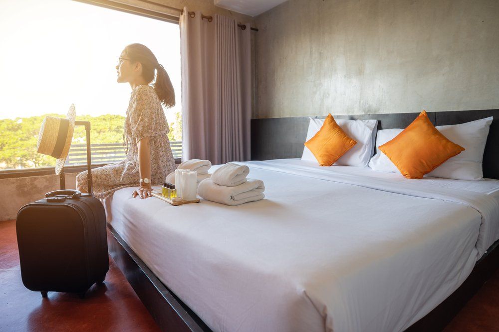 Fiatal turista nő ül a hotel szobájában az ágyon