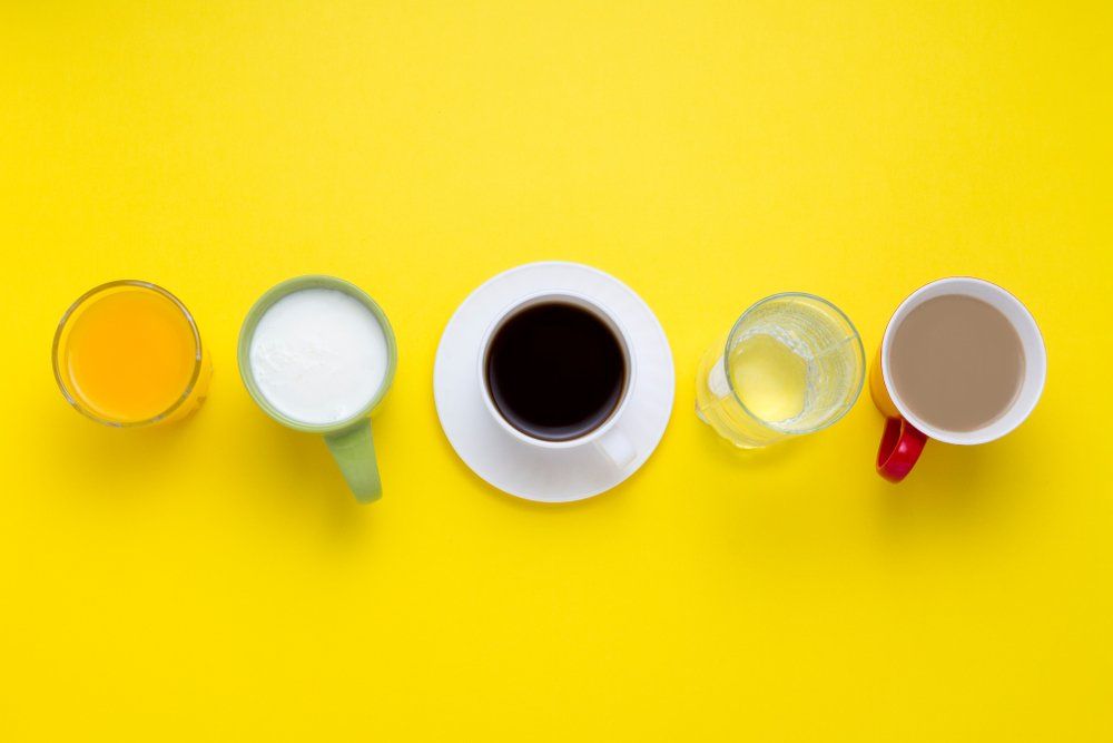Különböző italok: narancslé, tej, fekete kávé, víz, kakaó, sárga háttéren