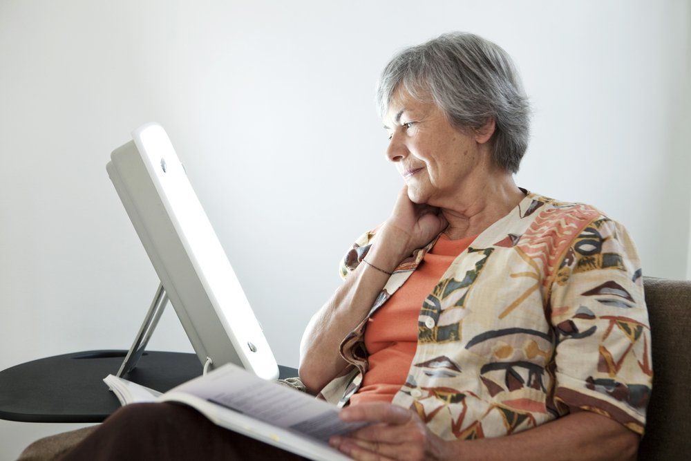 Fényterápiás doboz előtt ülő idősebb nő