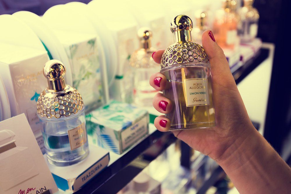Guerlain parfümös üveget tart egy női kéz