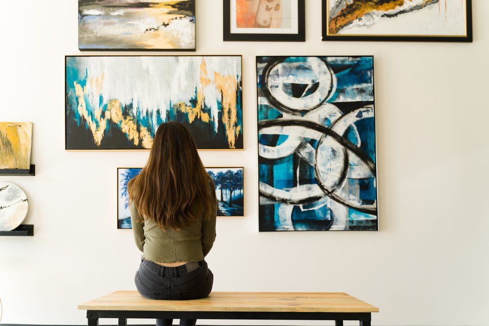 egy nő nézi a festményeket a falon