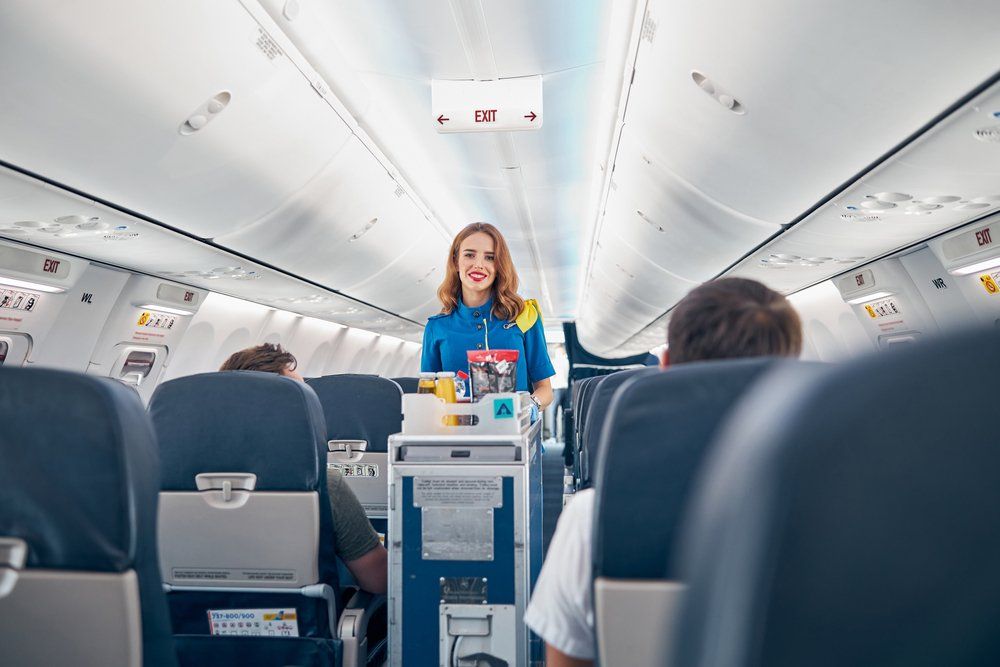 Légiutas-kísérő az ételt szolgálja fel a repülőn az utasoknak kék egyenruhában 