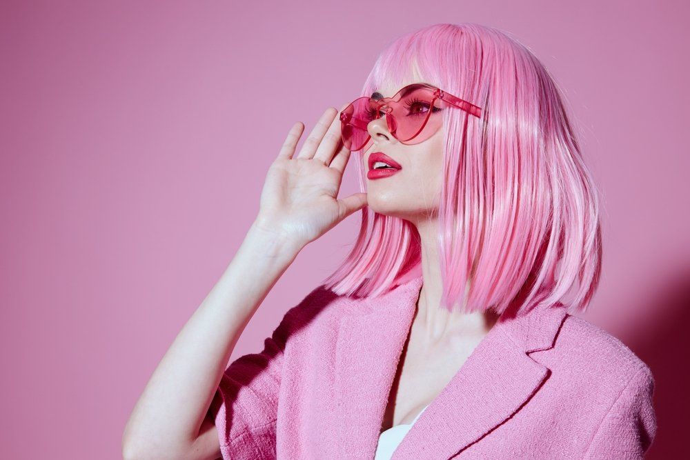 Rózsaszín hajú nő pink napszemüvegben néz a távolba