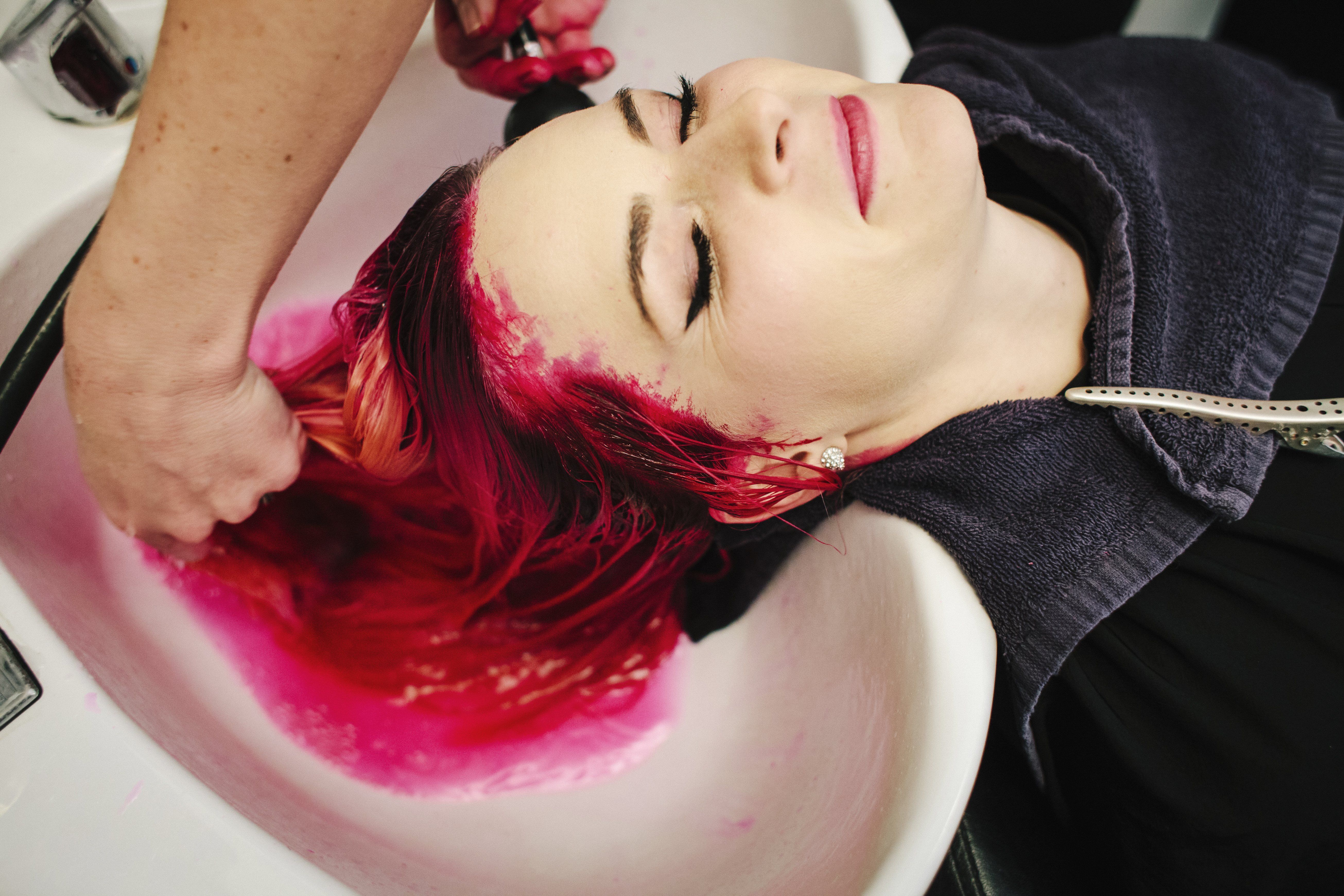 egy nő hajából mossák ki a festéket a fodrászatban