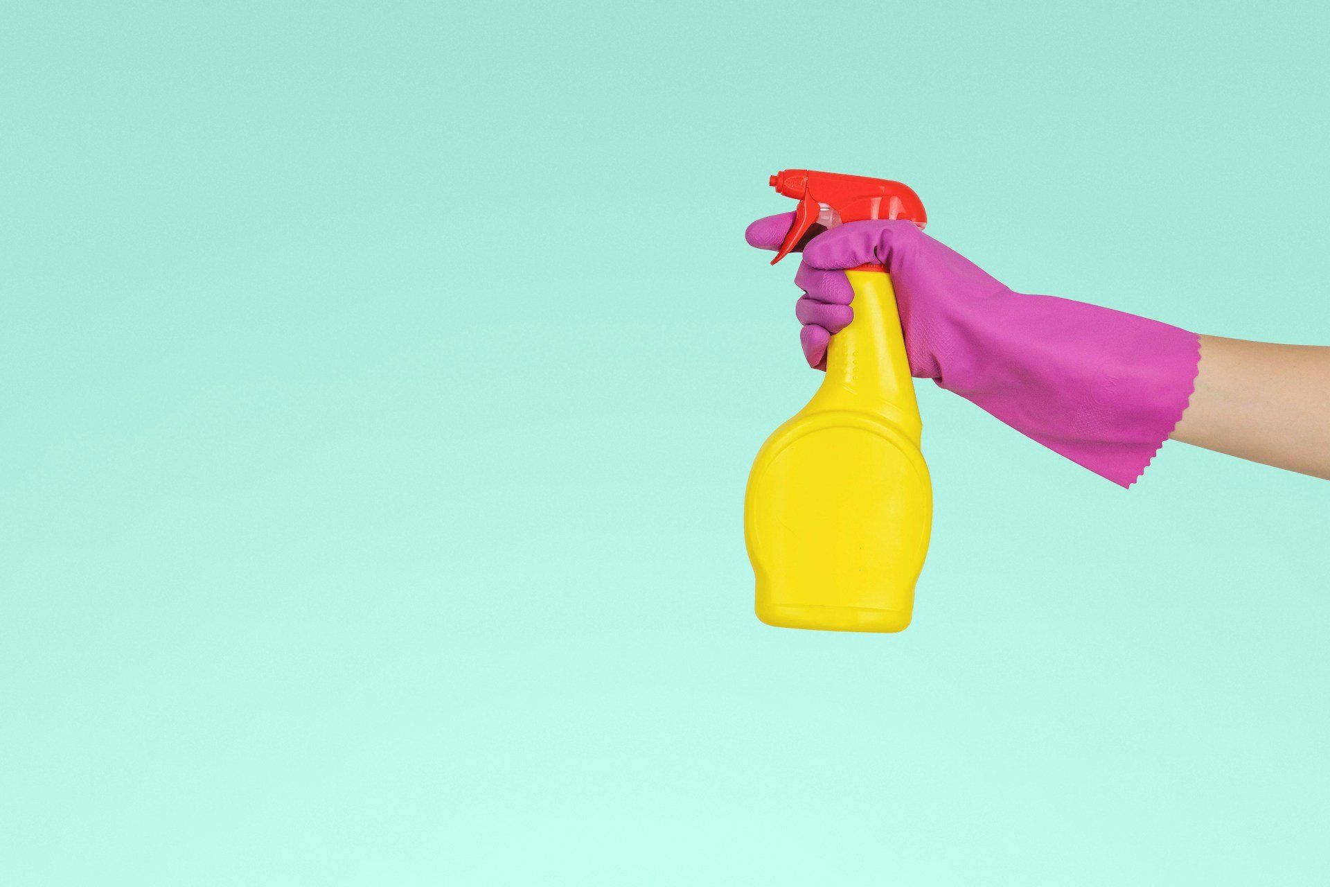 Sárga műanyag szórófejes flakont tartó gumikesztyűs kéz