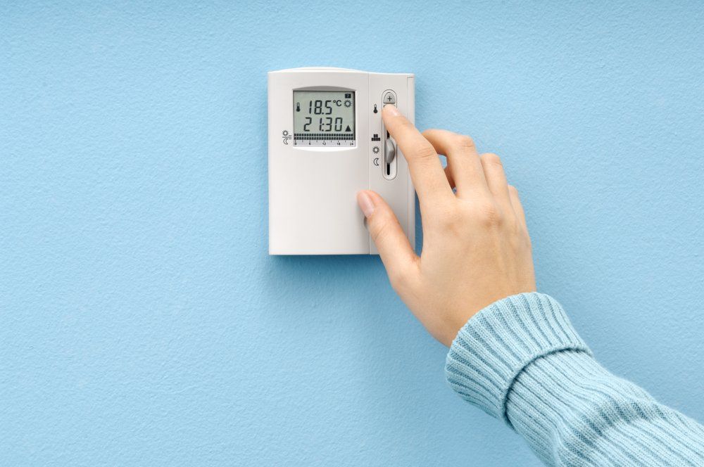 Szobahőmérséklet-szabályozás termosztáttal, női kéz