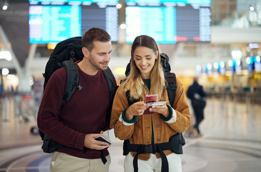 Repülőtéren álló pár nézi a nő mobilját