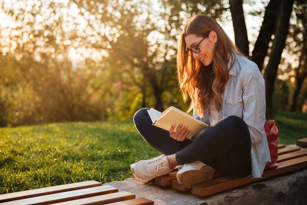 Parkban könyvet olvasó nő
