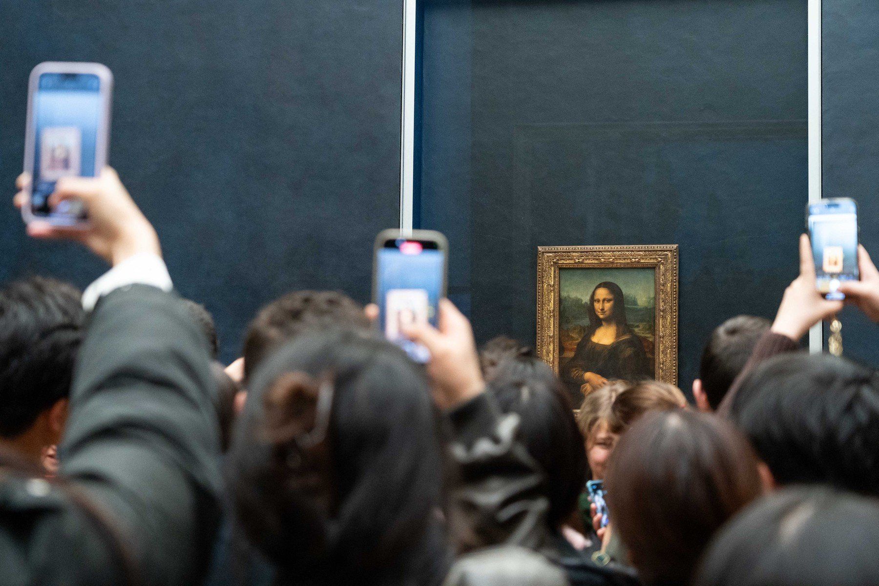Látogatók fényképezik a Mona Lisa című festményt telefonjukkal a párizsi Louvre Múzeumban 2023. december 12-én