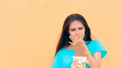 woman having toothache while eating chocolate