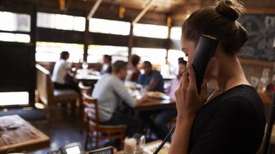 Fiatal pincérnő felveszi a foglalást telefonon az étteremben