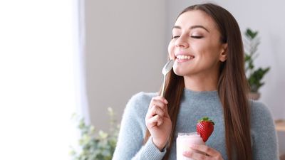 egy nő epres joghurtot eszik boldogan