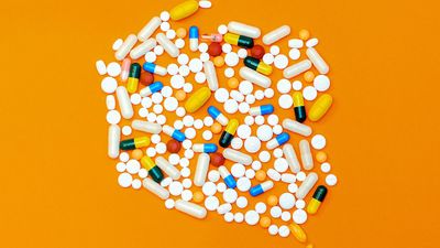 Különböző vitaminok és tabletták narancssárga háttér előtt