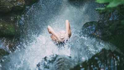egy nő zuhanyzik hideg vizzel egy forrásnál