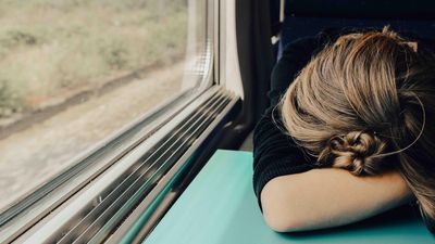 Egy nő alszik a vonaton fejét az asztalra hajtva 