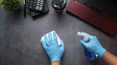 Egy ember gumikesztyűben takarítja az íróasztalát