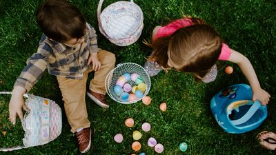 Két gyerek húsvéti tojásokat gyűjt a földön ülve