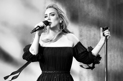 Adele énekel mikrofonba, fekete ruhában