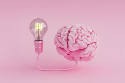 Rózsaszín agy villanykörtéhez kötve, rózsaszín háttér előtt