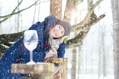 Szőke nő, kék kabátban a hóban borozik