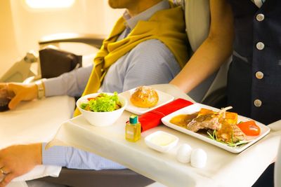 légiutas-kísérő hozza a meleg ételt az utasnak a repülőn
